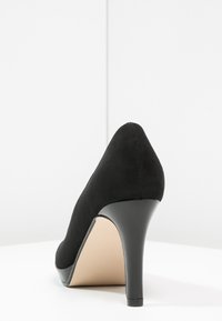 Černá nubuková lodička na vysokém podpatku s špičatou špičkou a lesklým černým podpatkem. Hladký povrch s béžovou stélkou a minimem švů.