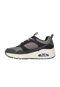 Sneakers sportivi con tomaia in rete grigia, accenti neri e sovrapposizioni verde oliva. Presentano una suola intermedia bianca e un'imbottitura d'aria visibile.