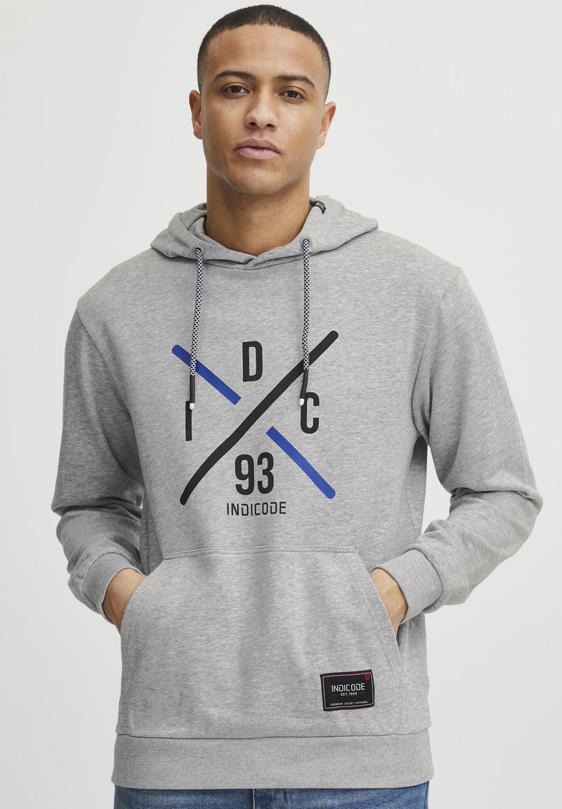 Gray hoodie with a front pocket, featuring black, blue, and gray graphic elements and a stitched logo label at the hem. Drawstring hood.