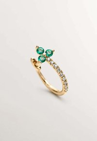 Anillo de oro que presenta dos gemas de esmeralda y una fila de piedras claras a lo largo de la banda, con un acabado liso y pulido.