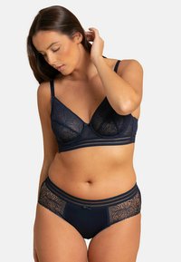 Ensemble de soutien-gorge et culotte marine avec des détails en dentelle et des bretelles réglables. Le soutien-gorge comprend un fil structurant et une large bande, tandis que la culotte est ornée d'un accent en nœud.