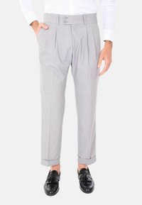 Pantaloni a pieghe grigi con cintura a doppio bottone, caratterizzati da un taglio dritto e orli risvoltati, abbinati a mocassini neri.