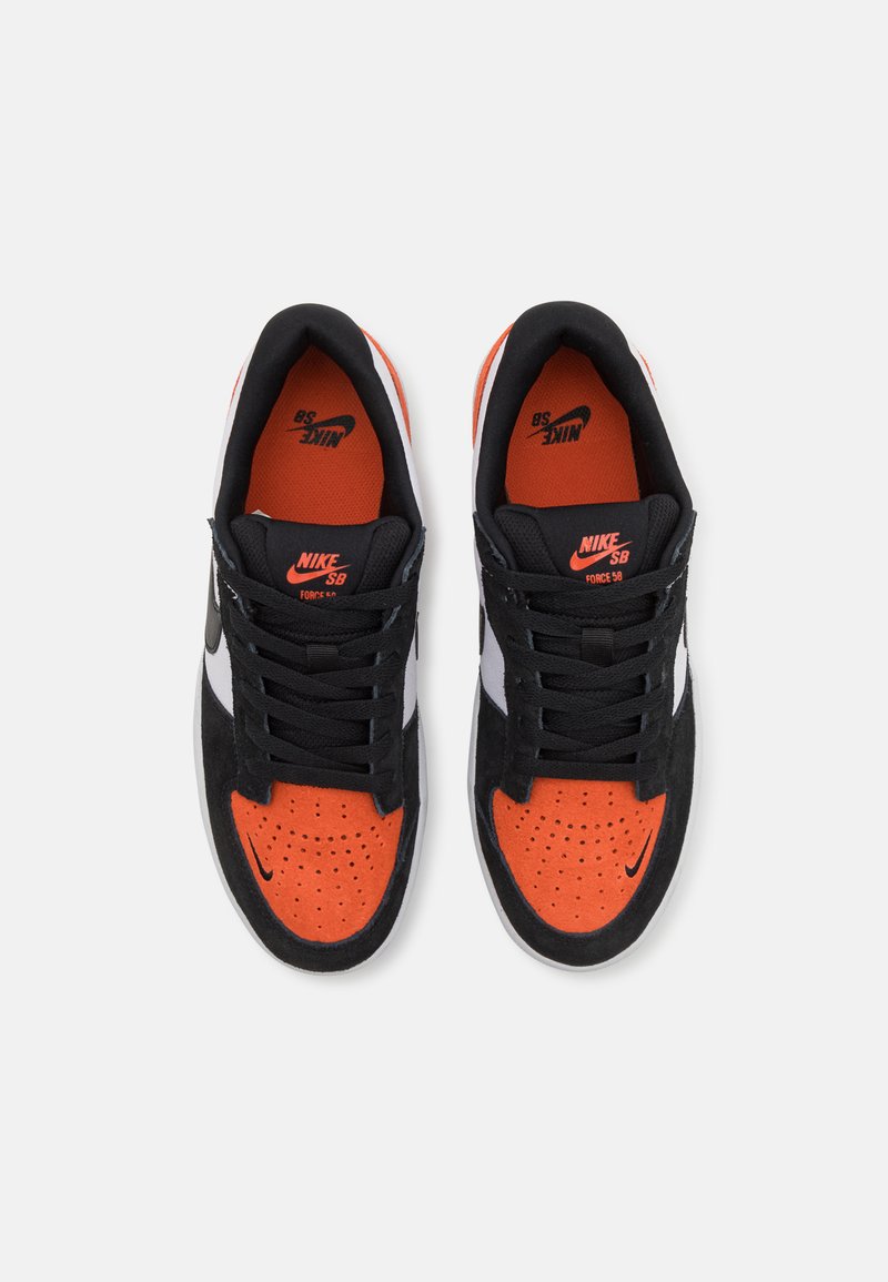 Baskets en daim noir avec une boîte à orteils perforée orange, lacets noirs, accents latéraux blancs et un logo rouge sur la languette.