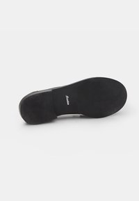 Black shoe sole with textured rubber for grip, featuring a raised logo "Bata" and smooth edges. Flat design with no additional embellishments.