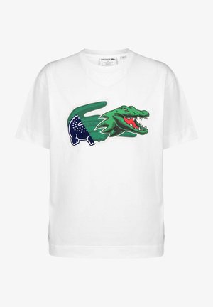 Wit Lacoste T-shirt met een grote gestileerde groene en marineblauwe krokodillengrafiek met een open mond en scherpe tanden aan de voorkant.