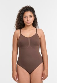 Bodysuit marrone con spalline sottili, caratterizzato da un collo rotondo e design senza cuciture. Tessuto morbido e elastico con una texture liscia.