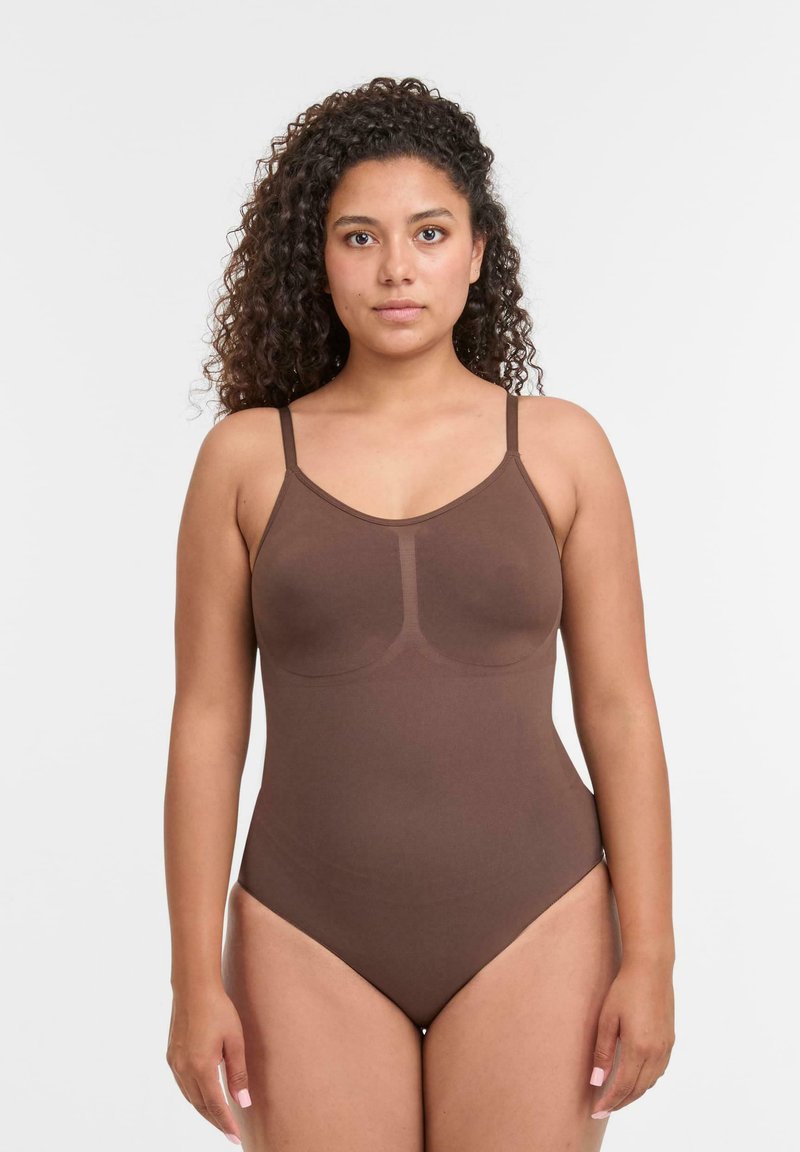 Bodysuit marrone con spalline sottili, caratterizzato da un collo rotondo e design senza cuciture. Tessuto morbido e elastico con una texture liscia.