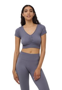 Szary prążkowany krótki top z dekoltem w kształcie V, krótkimi rękawami i marszczeniami na środku. Materiał wydaje się elastyczny i dopasowany.