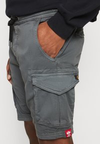 Grå cargo shorts laget av bomullsblanding, med strikk i livet, sidelommer og en lomme med merkeetikett på låret.