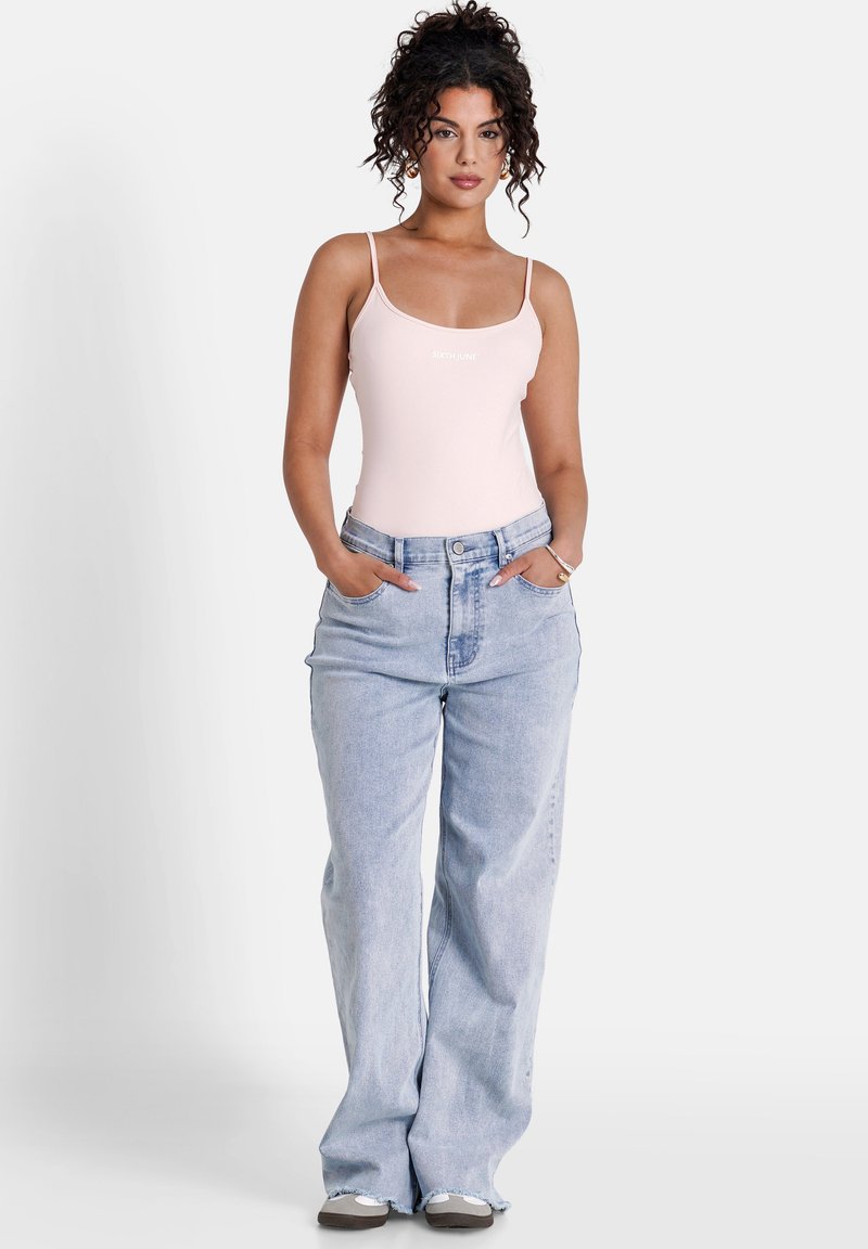 Ljusrosa bodysuit med tunna axelband och en logotyp. Ljusblå vida jeans med framfickor och hög midja.