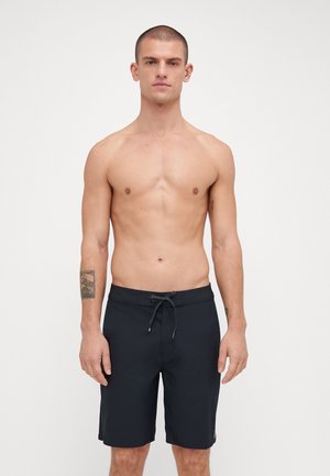 Shorts de baño negros para hombre, con cintura ajustable mediante cordón, frente plano, diseño hasta la rodilla y color sólido sin patrones ni acentos.