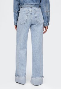 Svetlomodré široké rifle z denimu s vysokým pásom, dve zadné vrecká a zatočené manžety. Hladká textúra, neformálny dizajn.