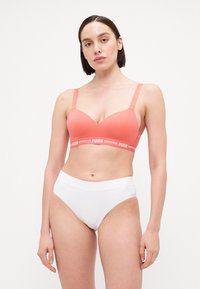 Coral bra with a smooth texture, V-shaped cup, and branded elastic band. White high-waisted briefs, seamless design, and soft material.