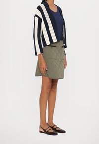 Pruhovaný pletený kardigan v námořnické modři a smetanové barvě, žebrovaný námořnický top, prošívaná olivově zelená sukně a dvoubarevné baleríny s pásky a ozdobami.