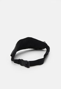 Bolsa de cinturón ajustable negra hecha de material de malla texturizada. Presenta un cierre de hebilla y una correa suave para un uso cómodo.