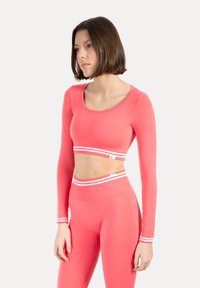 Langärmliges, kurzes Oberteil und hoch taillierte Leggings in leuchtendem Pink. Mit weißen horizontalen Streifen an Bund und Bündchen. Glatte Textur.