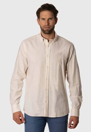 Camisa de manga larga, con botones, en beige claro, hecha de un tejido texturizado. Presenta un clásico cuello y un sutil logo bordado en el pecho.
