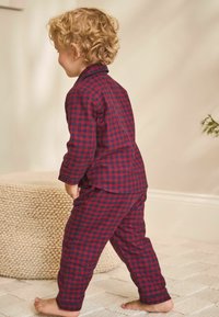 Rød og marineblå ternet pyjamassæt til børn, der inkluderer en langærmet bluse og matchende bukser, fremstillet af blødt stof.
