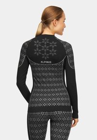 Czarny sportowy top z długimi rękawami, z geometrycznymi wzorami. Materiał wydaje się elastyczny, ma dopasowany krój. Logo umieszczone z tyłu.