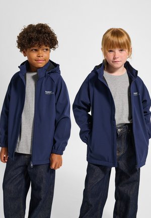 Marineblå zip-up jakker med hætte, lavet af tekstureret stof. Båret over grå t-shirts og mørke denim jeans. To børn poserer side om side.