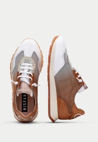 Sneaker con punta in pelle bianca, lati in rete marrone e dettagli grigi. Presenta lacci rotondi e una suola testurizzata con un logo. Design leggero.