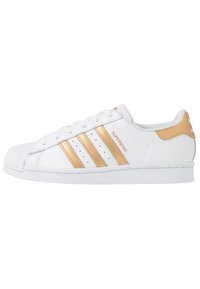 Białe sneakersy Adidas Superstar ze złotymi akcentami, z trzema złotymi paskami, teksturowanym gumowym czubkiem i wyściełanym kołnierzem.