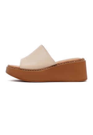 Beżowy sandał na klinie na wsuwkę z zakrytą przednią ramiączką i grubą brązową podeszwą platformową, widok z boku na białym tle.