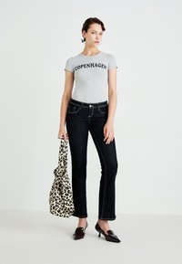 Grå t-skjorte med korte ermer og "COPENHAGEN" trykk, sammen med mørkeblå utsvingte jeans og en leopardmønstret veske. Mørke sko med en liten hæl.