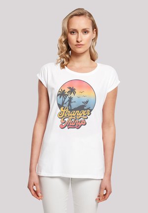 Weißes T-Shirt mit kurzen Ärmeln, das einfarbig lebendige Grafiken von Palmen, einem Sonnenuntergang und dem Schriftzug "Stranger Things" in fetter Schrift zeigt.