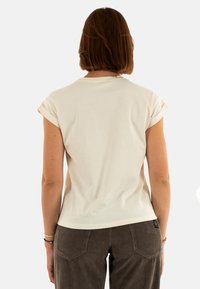 T-shirt corto a maniche corte beige chiaro con risvolti, tessuto morbido, design aderente e un delicato dettaglio di cucitura sul retro.