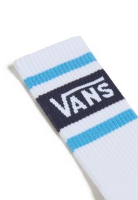 Calcetín de algodón blanco con rayas azules y marinas, con un destacado logo de Vans en blanco sobre un fondo oscuro. Textura acanalada en la parte superior.