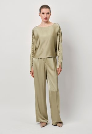 Licht olijfgroen zijden blouse met een brede halslijn en gedrapeerde mouwen; gecombineerd met bijpassende broek met wijde pijpen. Getextureerde stof met een subtiele glans.