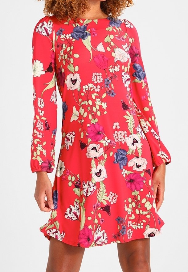Robe rouge à manches longues avec motif floral multicolore et ourlet légèrement évasé portée par une personne visible des épaules jusqu'à mi-cuisse.