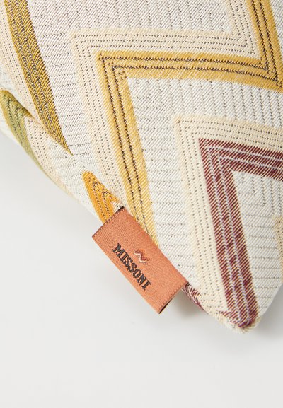Decorative pillow with a textured fabric featuring diagonal chevron patterns in yellow, green, and burgundy, with a visible Missoni label.