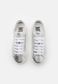 Silverfärgade metallicsneakers med vita snören, rundad tå och logodetalj på sidan. Slät textur med en ren, minimalistisk design.