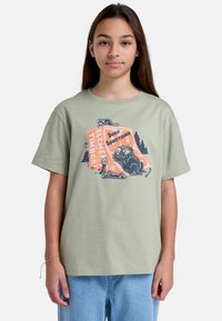 Lysegrøn bomulds t-shirt med et grafisk design af en bjørn, teksten "Byg noget" og skovelementer. Kortærmet, afslappet pasform.