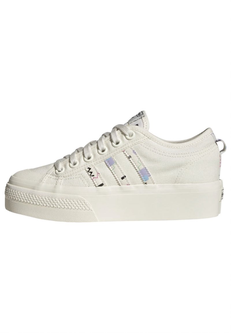 Baskets en toile blanches avec semelle en caoutchouc texturé, affichant trois accents rayés colorés sur le côté et des lacets ronds. Col légèrement rembourré.