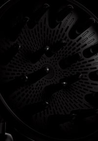 Accessoire diffuseur de cheveux noirs avec larges dents et base perforée, conçu pour un flux d'air uniforme lors du séchage des cheveux.