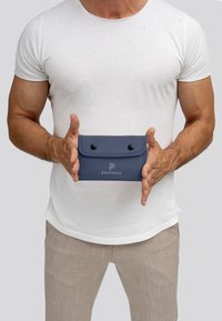 Marineblauwe pouch van soepel materiaal met een drukknoopsluiting, voorzien van een logo aan de voorkant. Compacte, rechthoekige vorm met afgeronde hoeken.