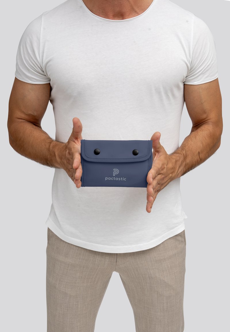 Marineblauwe pouch van soepel materiaal met een drukknoopsluiting, voorzien van een logo aan de voorkant. Compacte, rechthoekige vorm met afgeronde hoeken.