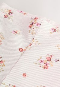 Light pink ribbed fabric featuring a floral pattern in soft pastel colors. The texture is smooth with delicate stitching.