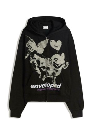 Črna zip-up kapuca iz mehkega blaga, opremljena z grafičnim tiskom winged figur, besedilom "enveloped" v beli in vijolični barvi ter sprednjim žepom.