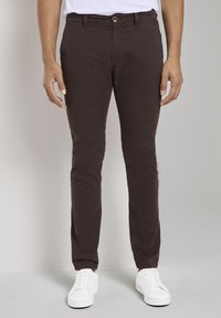 Chino marroni in cotone, con vestibilità slim, tasche frontali e chiusura con bottone. Abbinati a sneaker bianche.