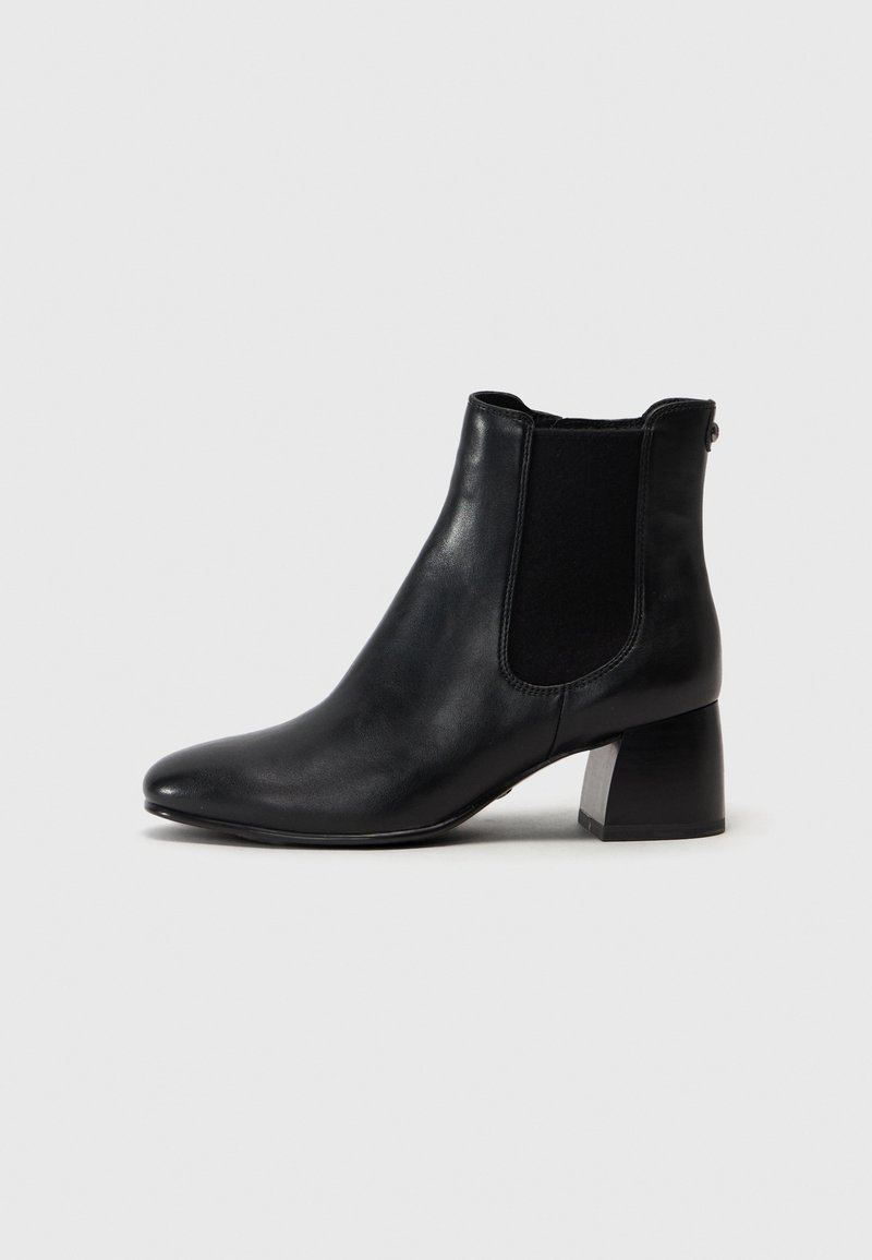 Botte à cheville en cuir noir avec talon bloc et panneau latéral élastique, vue de profil sur fond gris clair.