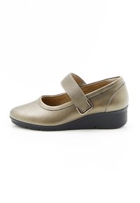 Zapato tipo Mary Jane en dorado metálico con puntera redonda, correa elástica ajustable y tacón bajo negro en cuña. Textura de cuero liso.