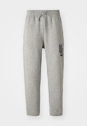 Pantalons de survêtement gris avec une taille élastique, cordon de serrage ajustable, et un patch « UA » sur le côté gauche. Fabriqués en tissu doux et texturé.