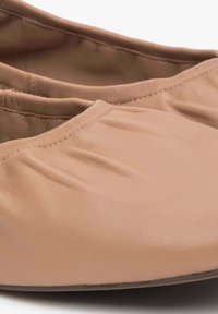 Nude skórzane baleriny o miękkiej fakturze z marszczonym szwem wzdłuż krawędzi i okrągłym czubkiem.
