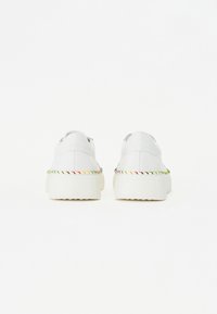 White sneakers with a smooth leather upper, featuring a colorful braided accent along the sole and a textured, chunky rubber outsole.