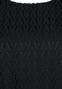Sort tekstureret stof med et zigzag-mønster, lagdelt med synlige sømme. Designet har en tredimensionel effekt.