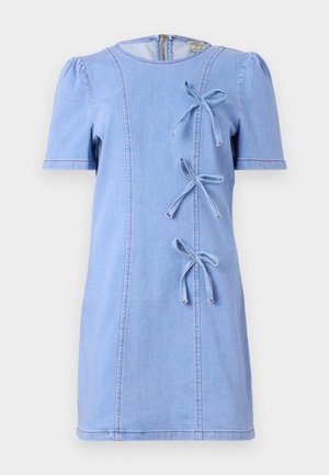 Vestuário em denim azul com mangas curtas e bufantes, gola redonda, três laços decorativos na parte da frente e detalhes de costura em contraste.